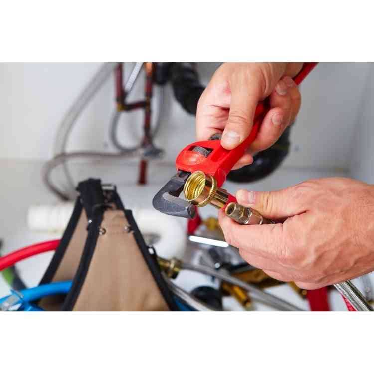 Plumber using an adjustable pipe wrench to thread a pipe fitting